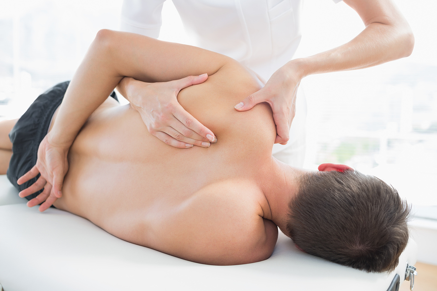 Professional female osteopath giving shoulder massage to a patient